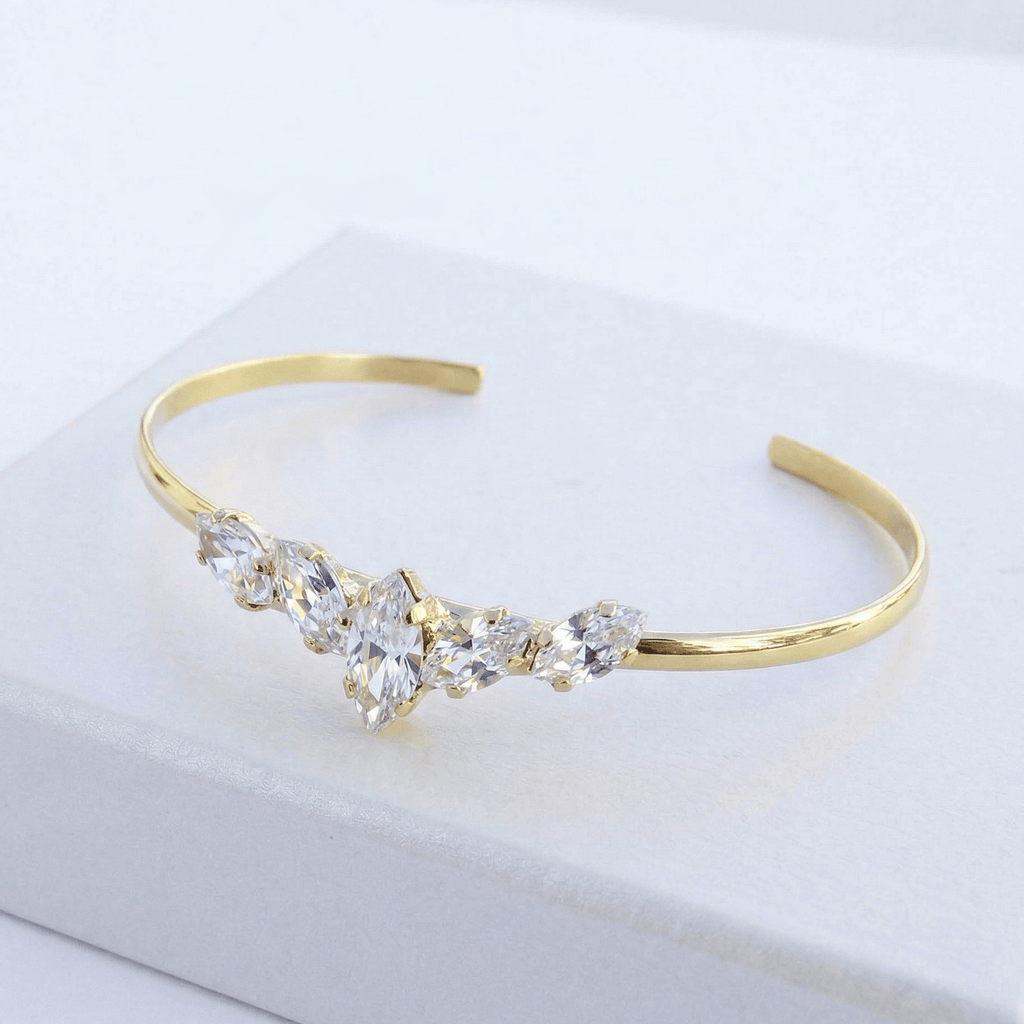 צמיד זהב עם אבני חן שקופות על משטח לבן